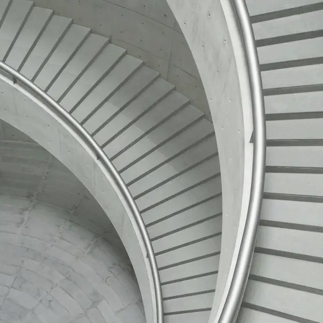Yukarıdan çekilmiş beton sarmal rampanın geniş yayları; basamaklar iç içe daralarak merkeze doğru iniyor.